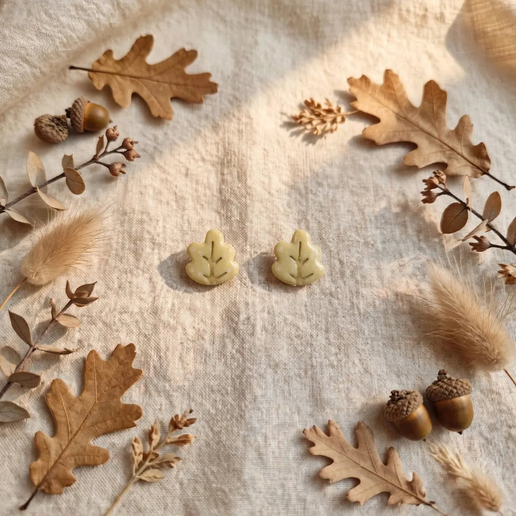 Puces d’oreilles feuille de chêne posées sur du lin, entourées de feuilles et de glands