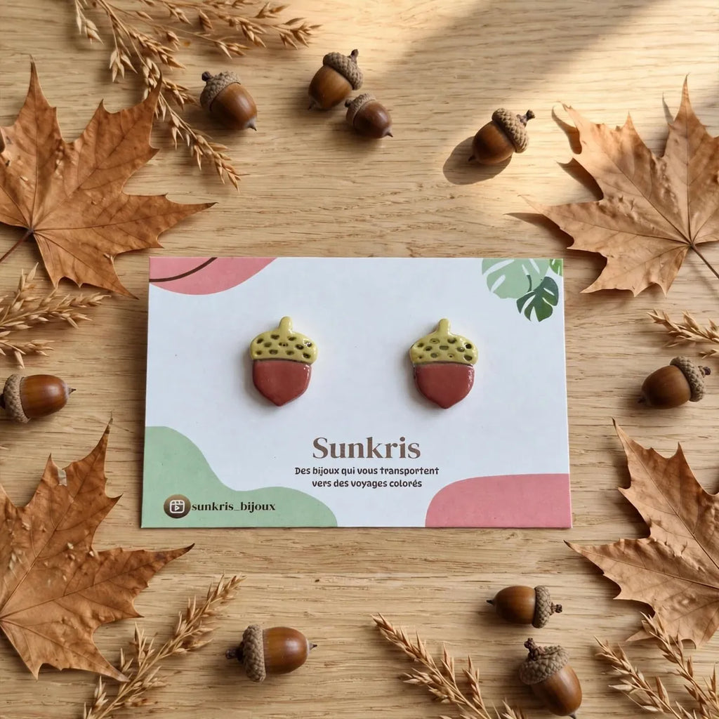 Paire de puces d’oreilles gland sur une carte Sunkris entourée de feuilles et de glands d’automne 