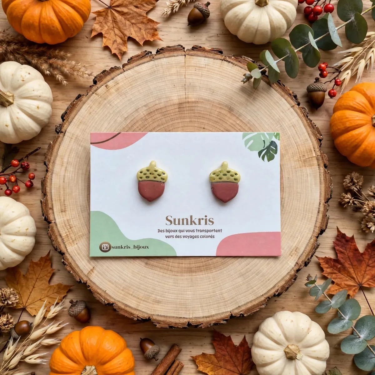 Puces d’oreilles gland sur une carte Sunkris posée sur un rondin de bois, avec citrouilles et feuilles d’automne