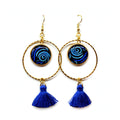 Paire de créoles cabochon bleu Sunkris, pompon bleu, posée sur fond blanc