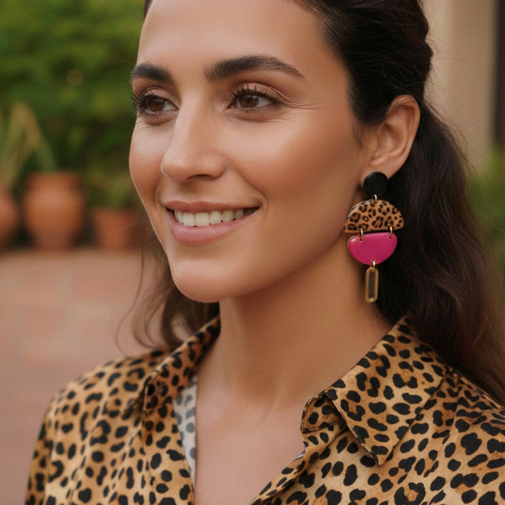 Femme portant des boucles d'oreilles pendantes léopard rose fuchsia faites main