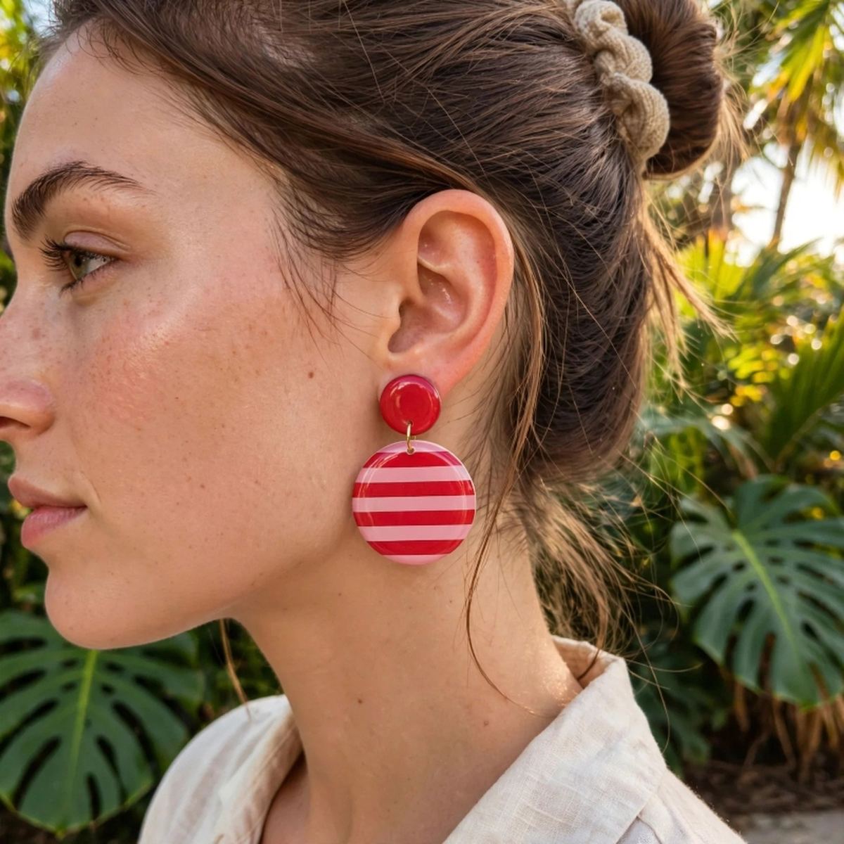 Femme aux cheveux tressés portant une boucle d'oreille ronde rayée rouge et rose Sunkris, en extérieur