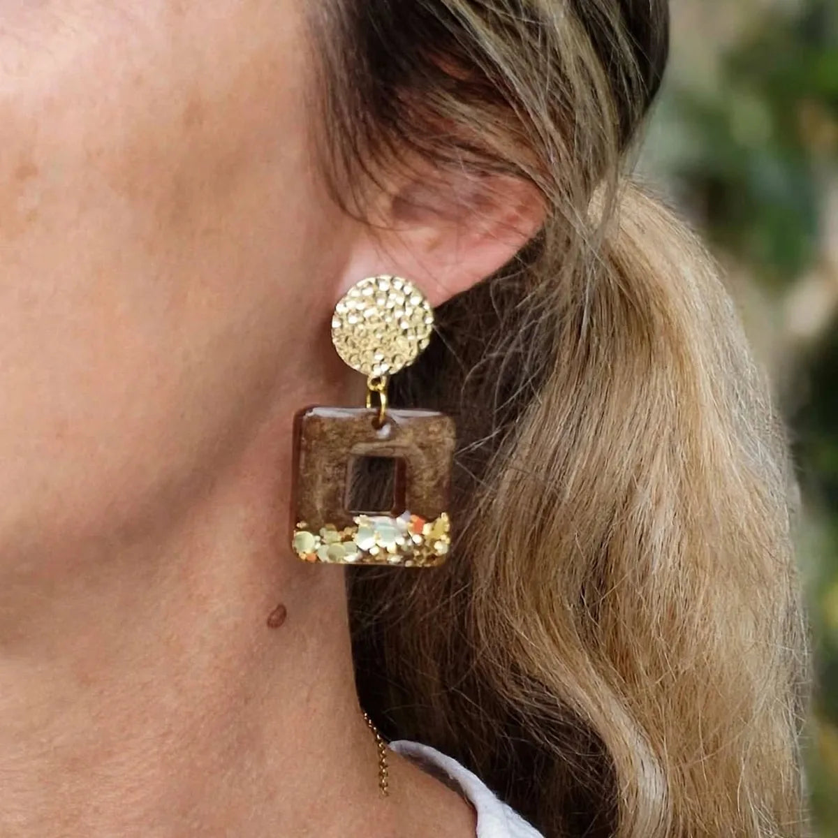 Boucle d'oreille carrée en résine marron et paillettes dorées portée à l'oreille