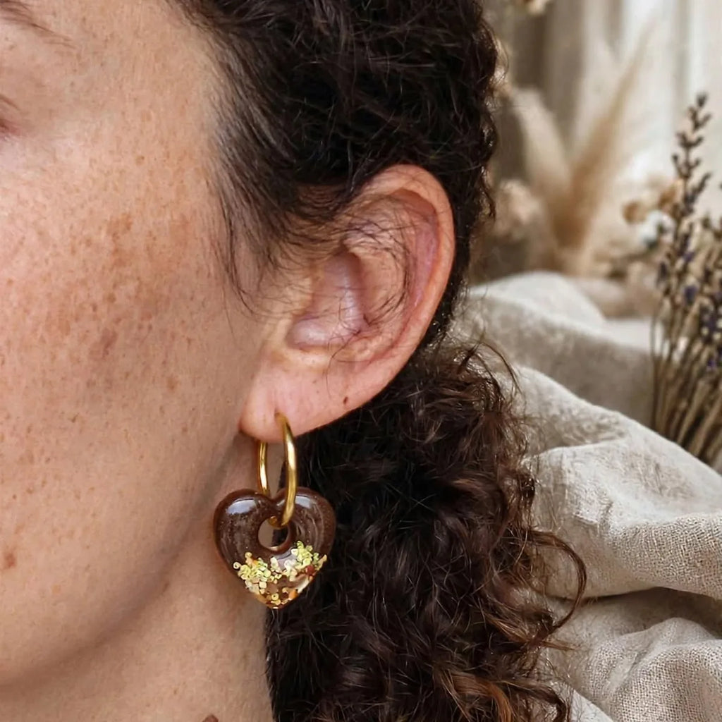 Boucle d'oreille cœur en résine marron et paillettes dorées, créole dorée, portée à l'oreille