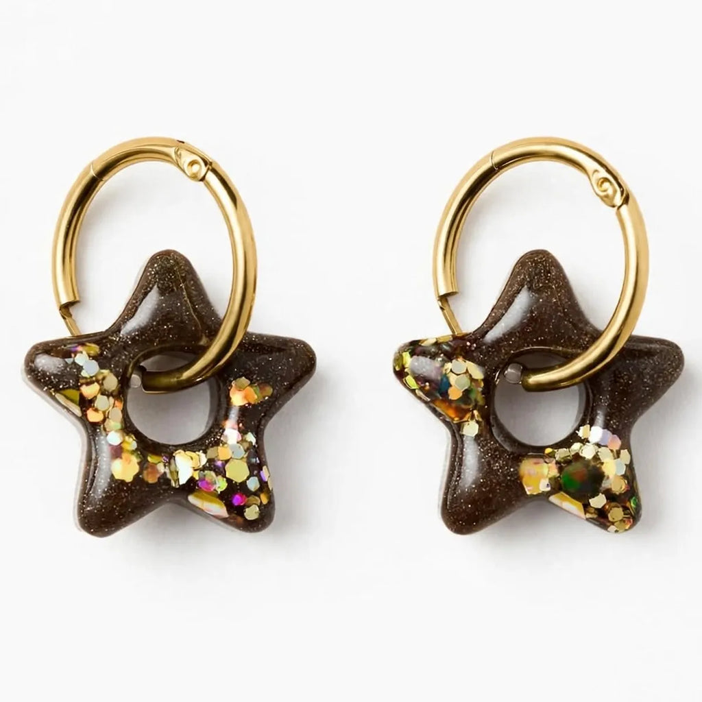 Paire de boucles d'oreilles étoile en résine marron et paillettes dorées sur créoles dorées, fond blanc