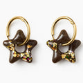 Paire de boucles d'oreilles étoile en résine marron et paillettes dorées sur créoles dorées, fond blanc