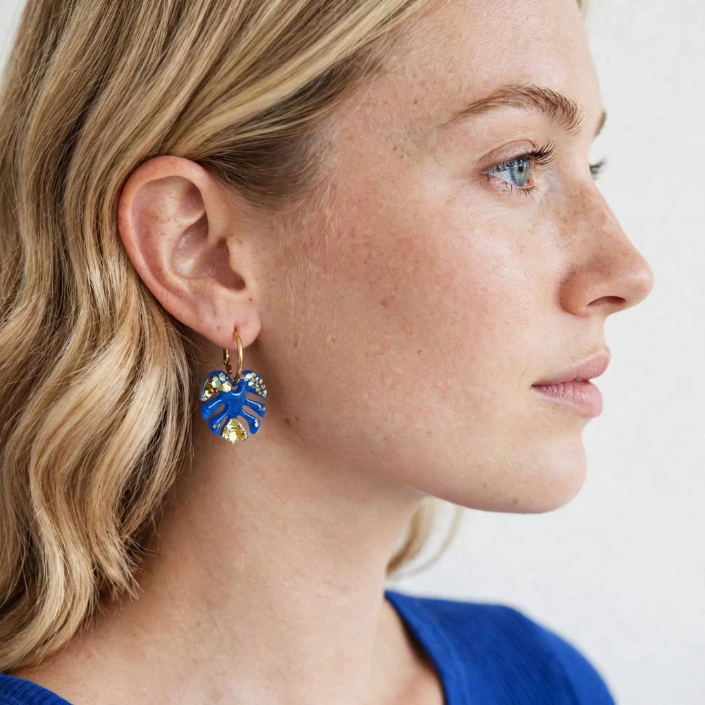Femme portant une boucle d'oreille créole feuille de monstera bleu et or Sunkris, vue de profil