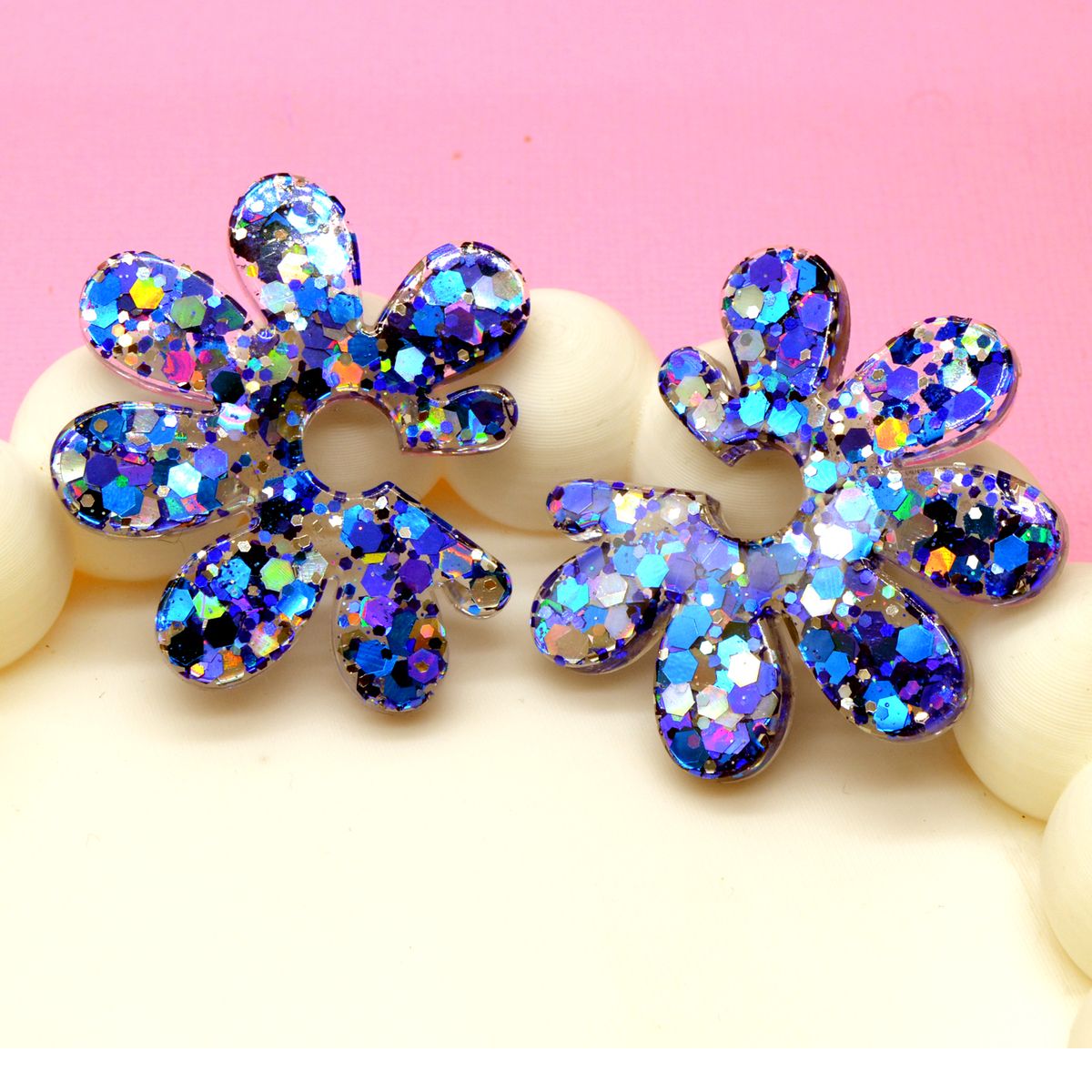 Gros plan sur les paillettes hexagonales bleues et holographiques de boucles d’oreilles fleur en résine